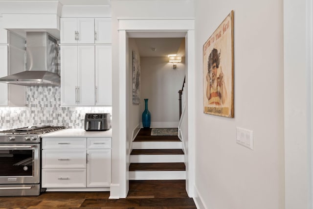 kitchen featuring white cabinetry, backsplash, dark hardwood / wood-style floors, gas stove, and wall chimney exhaust hood