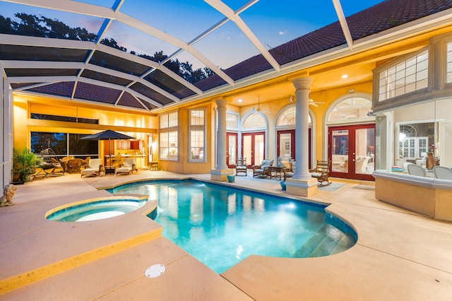 pool at dusk featuring ceiling fan, an in ground hot tub, french doors, a patio area, and glass enclosure