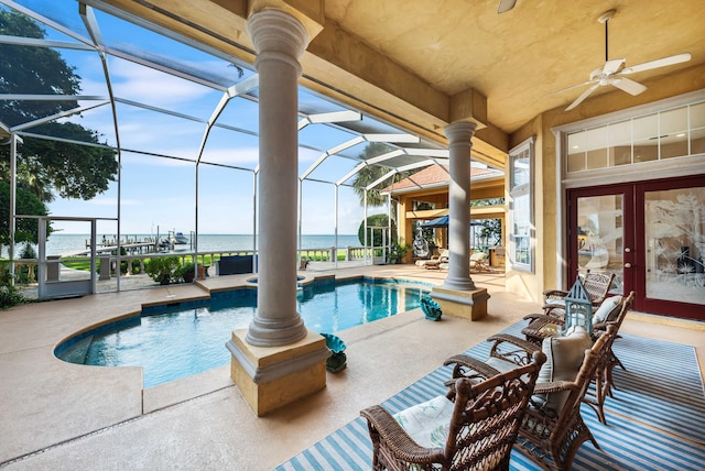 view of pool with a lanai, a patio, a water view, and ceiling fan