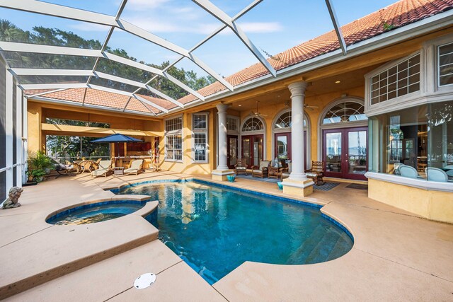 view of swimming pool with glass enclosure, an in ground hot tub, french doors, and a patio area