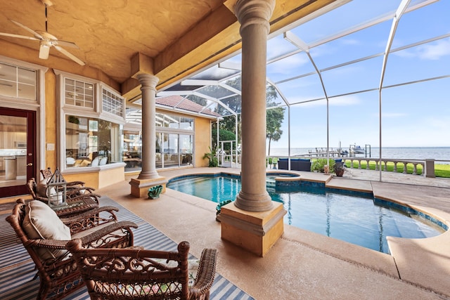 view of swimming pool with glass enclosure, a water view, ceiling fan, and a patio