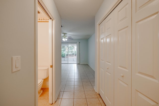 hall with light tile patterned floors and a textured ceiling