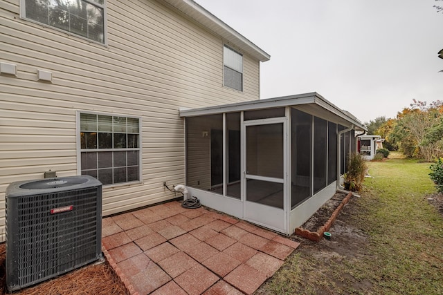 rear view of property with a sunroom, cooling unit, a patio area, and a lawn