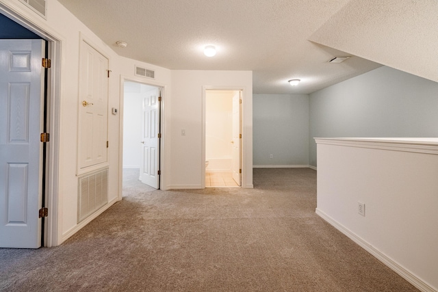 spare room with light carpet and a textured ceiling