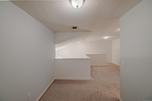 carpeted spare room featuring lofted ceiling and a textured ceiling