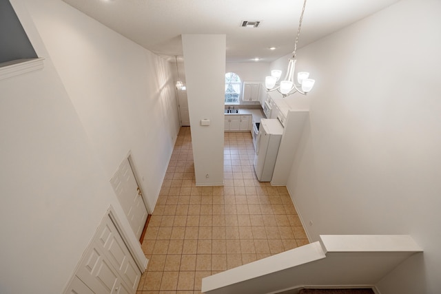 hall featuring light tile patterned floors and an inviting chandelier