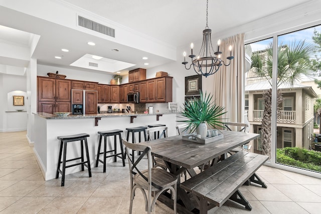 tiled dining room with an inviting chandelier and ornamental molding