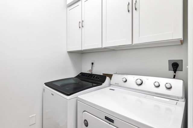 clothes washing area featuring washing machine and clothes dryer and cabinets