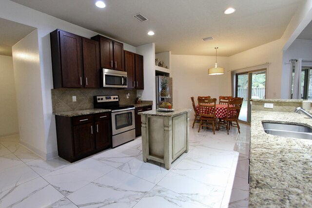 kitchen with stainless steel appliances, sink, and light stone countertops