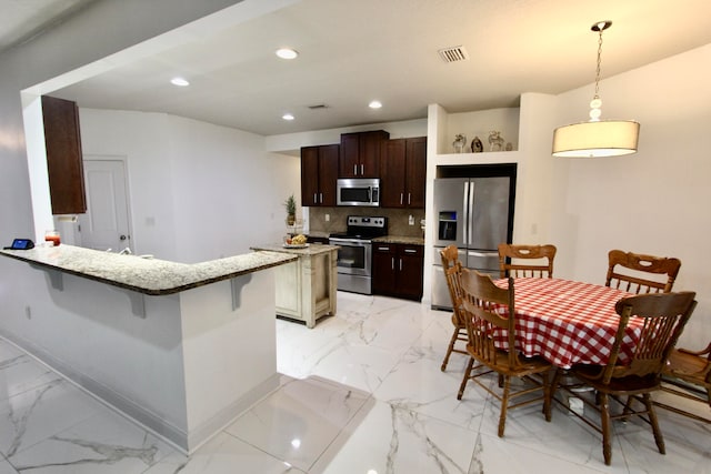 kitchen featuring appliances with stainless steel finishes, hanging light fixtures, a breakfast bar, decorative backsplash, and dark brown cabinetry