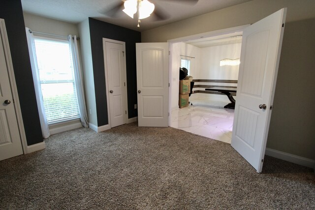 unfurnished bedroom with multiple windows, ceiling fan, and carpet