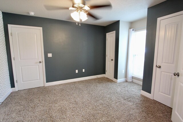 unfurnished bedroom with a textured ceiling, carpet, ceiling fan, and multiple windows