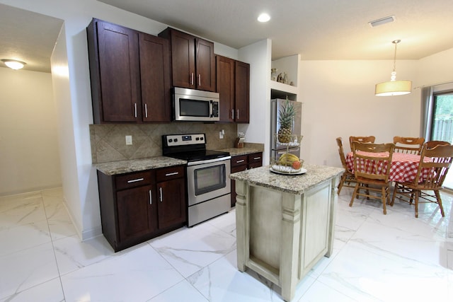 kitchen featuring hanging light fixtures, backsplash, light stone counters, stainless steel appliances, and a kitchen island