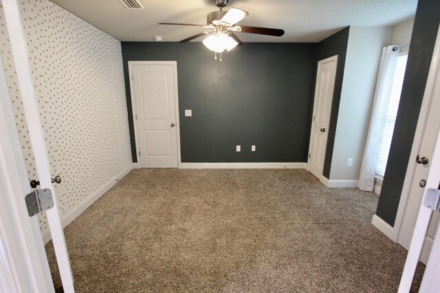 unfurnished bedroom featuring multiple windows, ceiling fan, and carpet floors