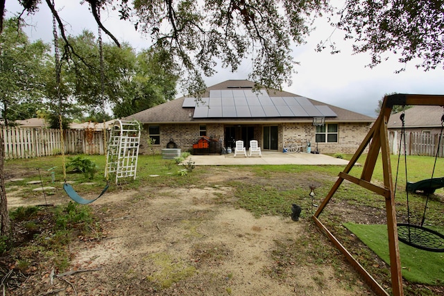 rear view of house featuring solar panels, a lawn, and a patio