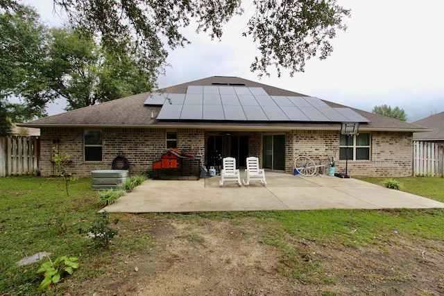 rear view of property featuring solar panels, a lawn, and a patio