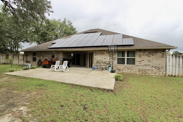 rear view of house with a lawn, solar panels, and a patio