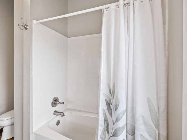 bathroom featuring toilet and shower / bath combination with curtain