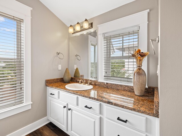 bathroom featuring vanity, vaulted ceiling, and hardwood / wood-style floors