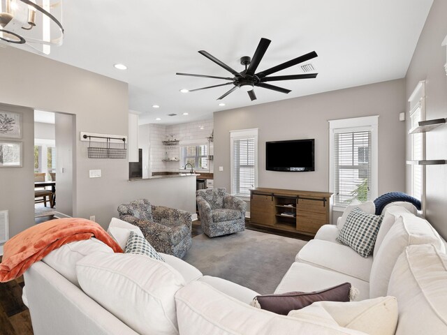 living room with ceiling fan with notable chandelier, a wealth of natural light, and wood-type flooring