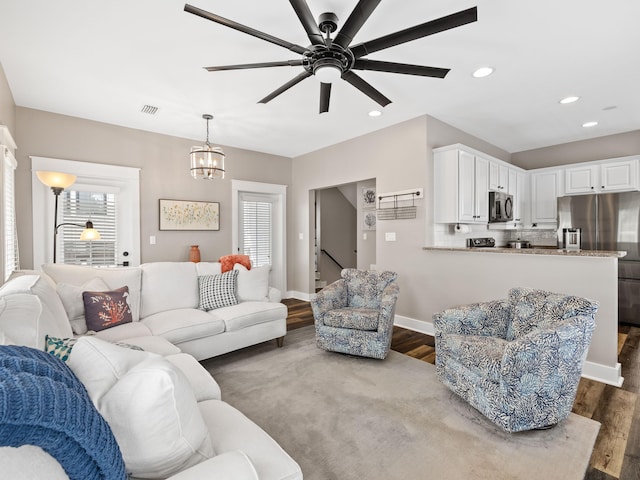 living room with dark wood-type flooring and ceiling fan with notable chandelier