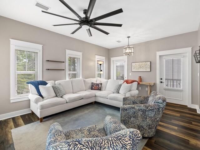 living room featuring ceiling fan with notable chandelier and dark hardwood / wood-style flooring