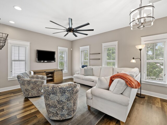 living room featuring ceiling fan with notable chandelier and dark hardwood / wood-style flooring