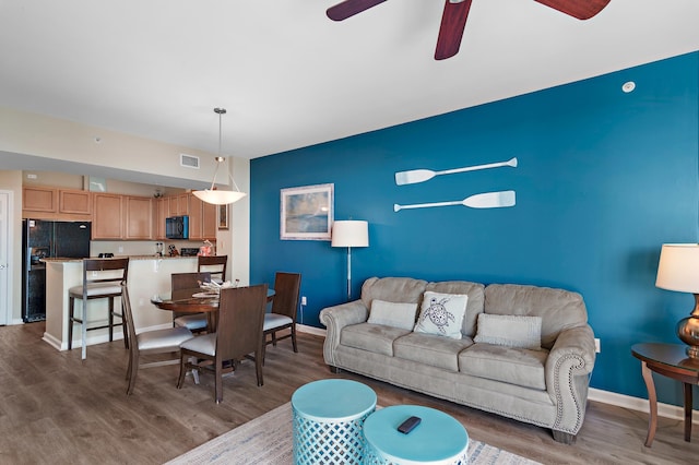 living room featuring ceiling fan and dark hardwood / wood-style flooring