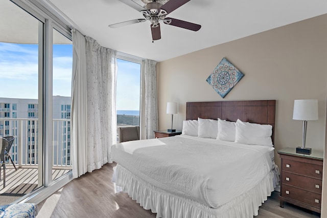 bedroom featuring ceiling fan, a wall of windows, light wood-type flooring, and access to outside