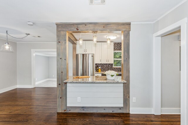 kitchen with pendant lighting, stainless steel refrigerator, light stone countertops, and dark hardwood / wood-style floors