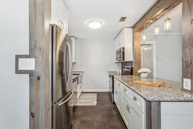 kitchen with light stone countertops, appliances with stainless steel finishes, hanging light fixtures, white cabinetry, and wooden walls