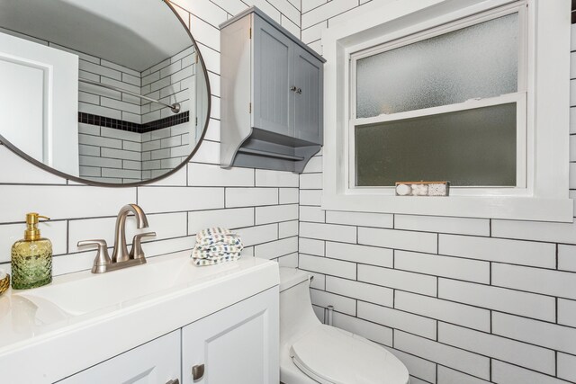 bathroom with vanity, toilet, tile walls, and walk in shower