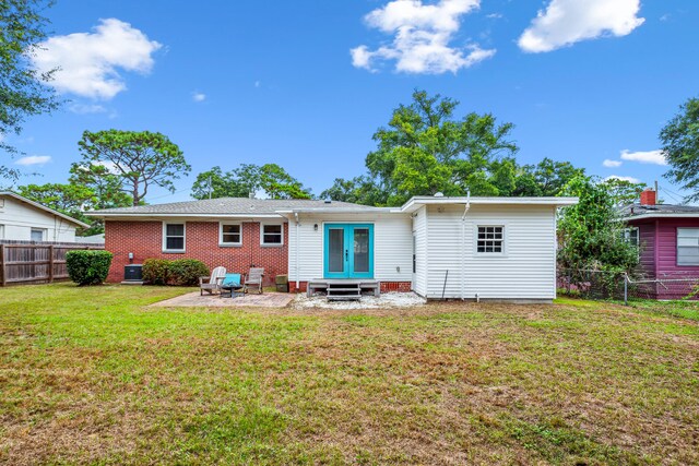 back of property with a yard, a patio, and central AC