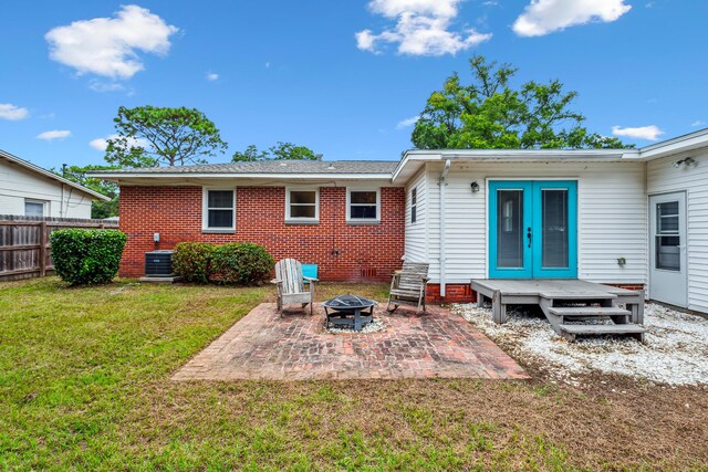 back of property with a fire pit, a patio, cooling unit, a lawn, and french doors