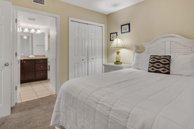 520 Santa Rosa Blvd Unit 301, Fort Walton Beach, FL 32548 - bedroom with a closet, ensuite bath, light tile patterned floors, light colored carpet, and visible vents