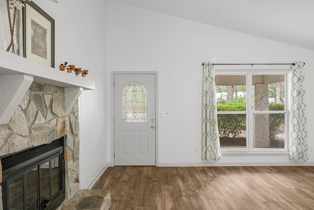 entrance foyer with vaulted ceiling, hardwood / wood-style floors, and a fireplace