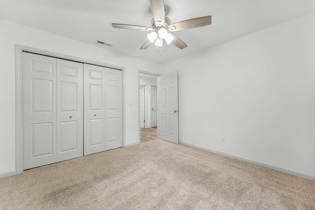 unfurnished bedroom with a closet, ceiling fan, and light carpet