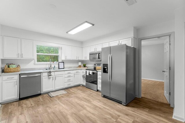 kitchen featuring appliances with stainless steel finishes, white cabinetry, light hardwood / wood-style flooring, and sink