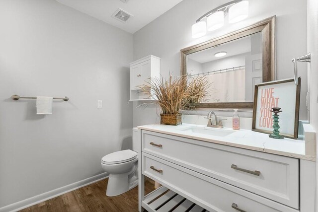 bathroom featuring wood-type flooring, toilet, and vanity