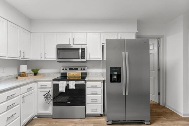 kitchen featuring white cabinets, light stone counters, stainless steel appliances, and light hardwood / wood-style flooring