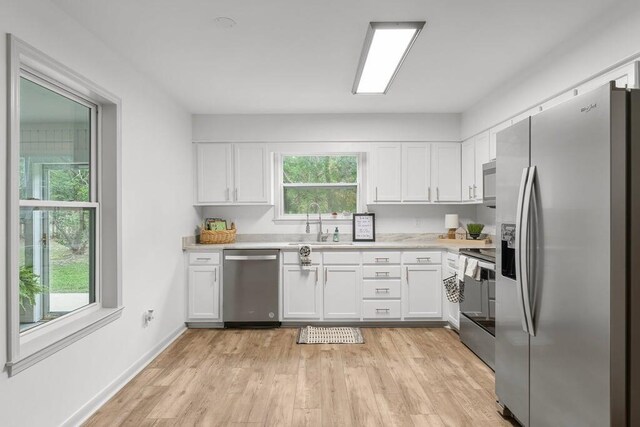 kitchen featuring light wood-type flooring, sink, appliances with stainless steel finishes, and white cabinets