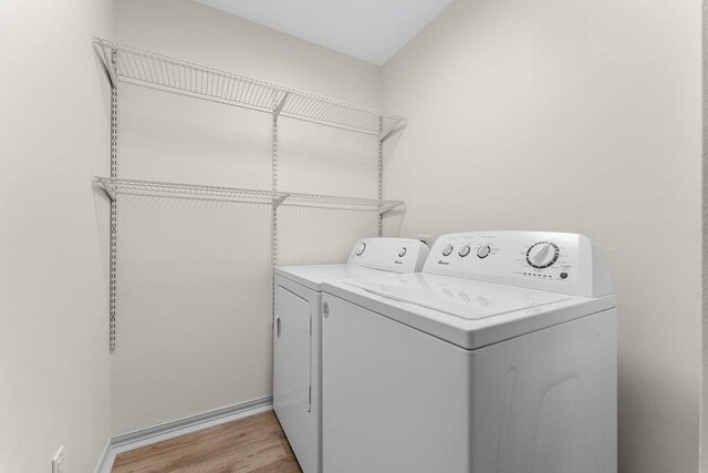 laundry room with light hardwood / wood-style flooring and washing machine and dryer