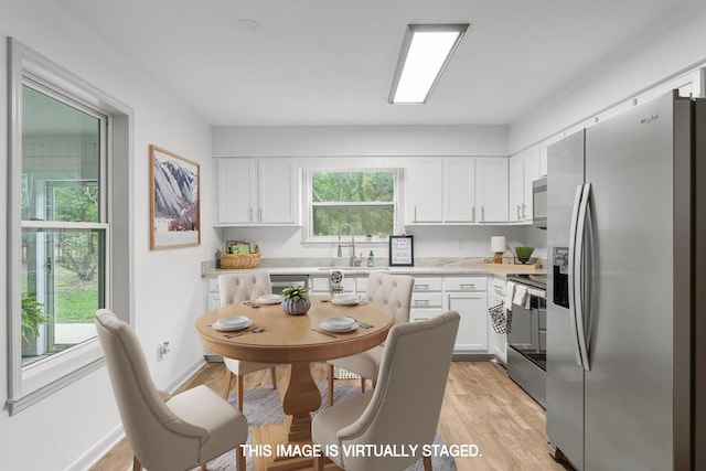 kitchen featuring white cabinetry, stainless steel appliances, sink, and light hardwood / wood-style flooring