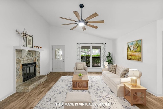 living room with ceiling fan, a fireplace, wood-type flooring, and vaulted ceiling