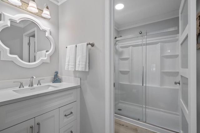 bathroom with crown molding, vanity, wood-type flooring, and walk in shower