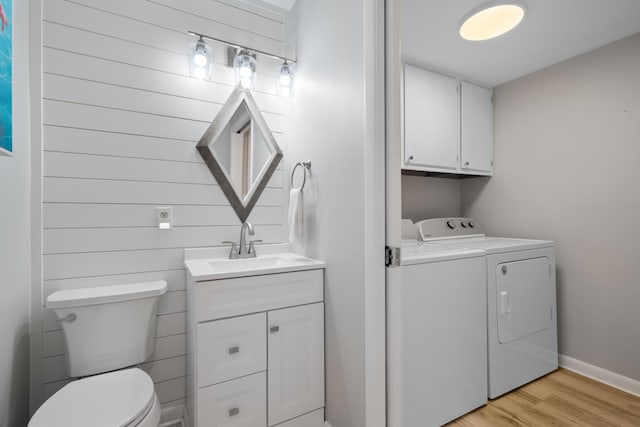 clothes washing area featuring washing machine and clothes dryer, sink, and light hardwood / wood-style floors