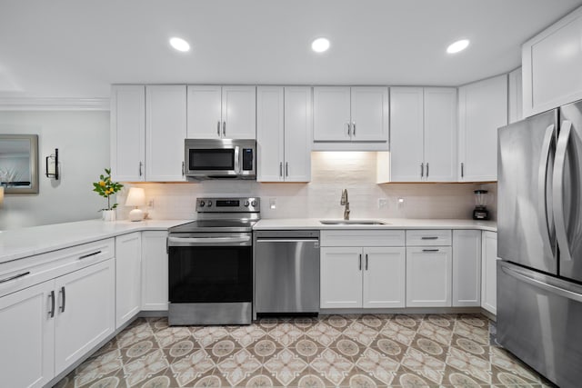 kitchen with backsplash, white cabinets, sink, ornamental molding, and appliances with stainless steel finishes