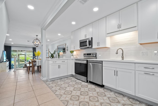 kitchen featuring sink, white cabinets, an inviting chandelier, and appliances with stainless steel finishes