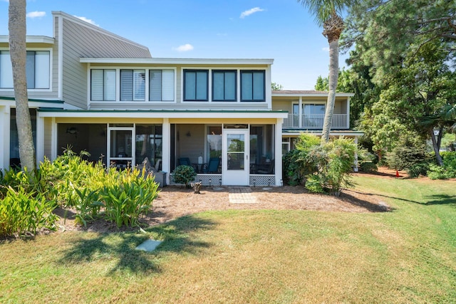 rear view of house featuring a lawn and a sunroom