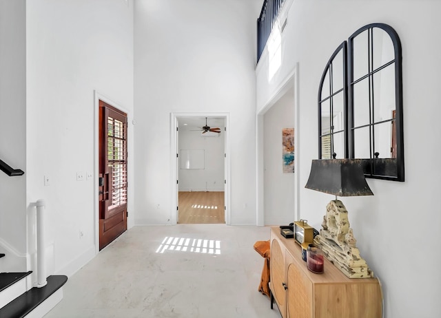 entryway with a towering ceiling, concrete floors, and ceiling fan